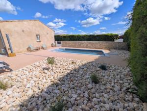 a backyard with a pool and a pile of rocks at Villa Le Nid du Pont d'Arc in Vallon-Pont-dʼArc