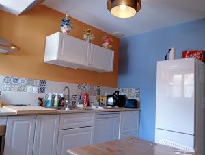 a kitchen with white cabinets and a white refrigerator at L'entre-potes in Sully-sur-Loire +7 photos