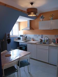 a kitchen with white cabinets and a table with chairs at L'entre-potes in Sully-sur-Loire