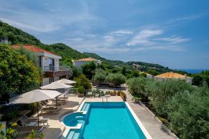 a pool at a resort with tables and umbrellas at Villa Svinjista in Budva