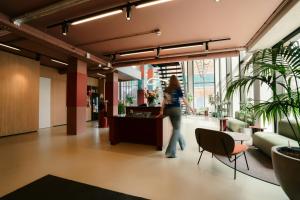 a woman walking through a lobby with plants at The Social Hub Eindhoven in Eindhoven