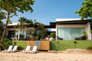 a house on the beach with chairs in front of it at Ma's Sea Beach House in Klong Muang Beach