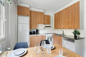 a kitchen with wooden cabinets and a wooden table with chairs at Central Lapland Apartment By Lapland Host in Rovaniemi +7 photos