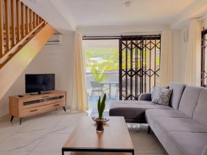 a living room with a couch and a tv and a table at Cove Holiday Apartments in Bel Ombre