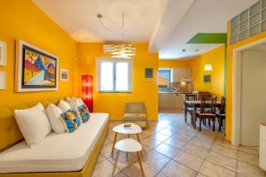 a living room with yellow walls and a couch and a table at Villa Kirki Apartments in Agia Effimia
