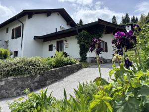 a white house with a stone wall and purple flowers at Bergnest Fieberbrunn in Fieberbrunn