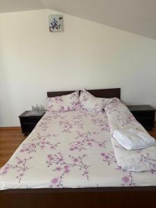 a bedroom with a large bed with pink flowers on it at Vila Lotus in Murighiol