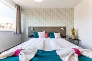a bedroom with a large white bed with colorful pillows at Nova City Apartments in Budapest