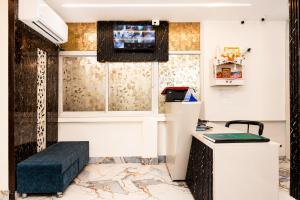 a waiting room with a blue ottoman and a tv on the wall at Hotel Golden Ring in Lucknow