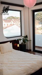 a bedroom with a white bed and two windows at CozyhomeDaLat in Khu Chi Lăng