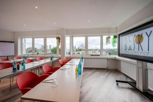 a conference room with tables and red chairs and a large screen at The Blasky in Frankfurt