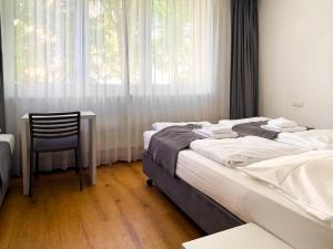 a bedroom with a bed and a chair and a window at mk hotel münchen max-weber-platz in Munich