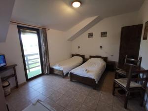 a room with two beds and a table and a window at Casa Juliana in Rîu Bărbat