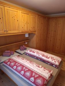 two beds in a room with wooden cabinets at Appartamento Marmolada in Pieve di Livinallongo
