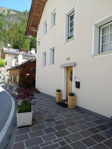 a white building with two potted plants on a street at Appartamento Marmolada in Pieve di Livinallongo