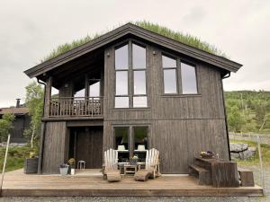 a small wooden house with a deck and chairs at Harevadet 217 in Volda