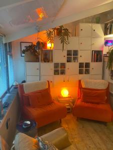 a living room with two orange chairs and a lamp at Spacious Studio by the sea, Garden & Parking in Marazion