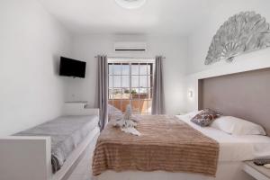 a white bedroom with two beds and a television at South Star Guesthouse in Quelfes +45 photos