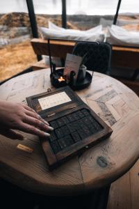 a person typing on a keyboard on a wooden table at Panorama Glass Lodge SOUTH in Hella
