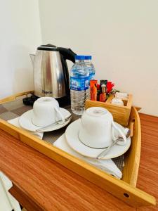 a table with two plates and a coffee pot and water at Grand Infinite Home Stay in Kandy