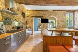 a large kitchen with stone walls and wooden counters at La Maison de Marie in Domme +32 photos