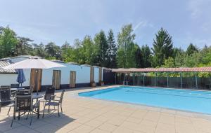 a patio with chairs and an umbrella and a pool at De Rode Vos - Enjoyment in the forest in Giethmen
