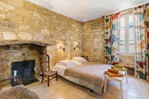 a stone walled bedroom with a bed and a fireplace at La Maison de Marie in Domme