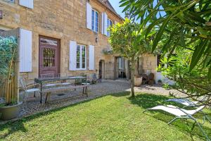 a garden with a bench in front of a building at La Maison de Marie in Domme