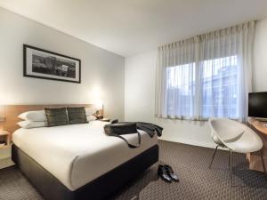 a hotel room with a bed and a desk and a television at ibis Melbourne Hotel and Apartments in Melbourne +116 photos