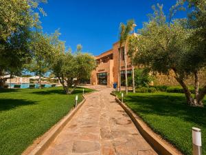 a walkway in front of a building with trees at Ourika Camp Suites Hotel & Resort in Marrakesh