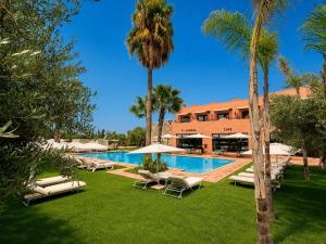 a resort pool with lounge chairs and palm trees at Ourika Camp Suites Hotel & Resort in Marrakesh