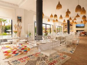 a dining room with white tables and chairs and large windows at Ourika Camp Suites Hotel & Resort in Marrakesh