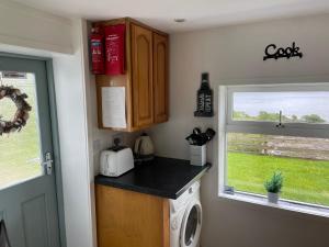 a kitchen with a washing machine and a window at Padraig cottage in Gortatlea