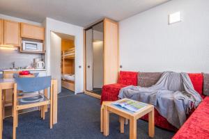 a living room with a red couch and a table at Résidence Pierre & Vacances Inter-Résidences in Tignes