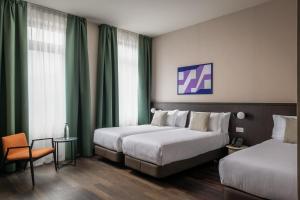two beds in a hotel room with green curtains at BYPILLOW Grand Central in Padova +77 photos
