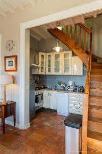 a kitchen with white cabinets and a staircase at Gîte du château d'Hodebert in Saint-Paterne-Racan