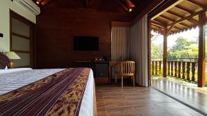 a bedroom with a bed and a balcony with a television at ChannaS villas in Payangan