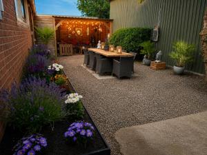 a patio with a table and some flowers at Holiday Home de Binnengouw incl Hottub in Hoogwoud +31 photos
