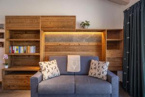 a blue couch in a living room with a book shelf at Shasta Mountain Lodge in Cavalese