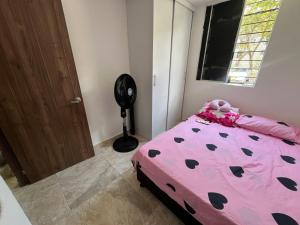 a bedroom with a pink bed and a fan at Ciudad Guabinas in Yumbo