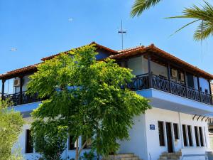 a white house with a balcony and a tree at Pension Anastasia in Ammouliani