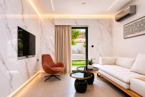 a living room with a white couch and a tv at Kayia City Garden, Luxury Suite with Private Garden in Heraklio