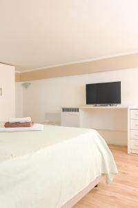 a white bedroom with a bed and a flat screen tv at Mediterraneum - Loft in Sannicola +5 photos