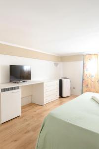 a white bedroom with a bed and a tv at Mediterraneum - Loft in Sannicola