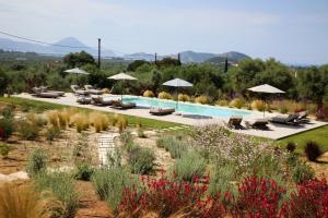 a pool in a garden with chairs and umbrellas at Villa Zeno in Tragána