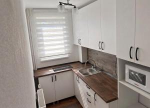 a small kitchen with white cabinets and a sink at Sissi Apartments in Gheorgheni