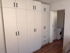 a white closet with white cabinets and a washing machine at Sissi Apartments in Gheorgheni +1 photo