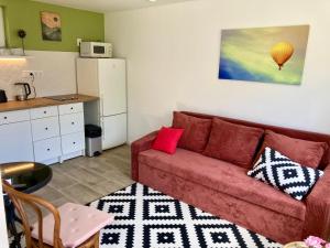 a living room with a red couch and a kitchen at Kisbirs Vendégház in Tokaj
