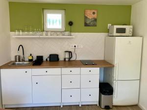 a kitchen with white cabinets and a white refrigerator at Kisbirs Vendégház in Tokaj