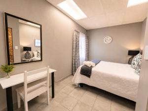 a bedroom with a bed and a desk and a mirror at Zhantique Guest House 2- Unit 10 in Boksburg